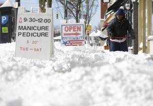 Jeff Williams widens the walking path in front of the storefront where he works in Patchogue, N.Y., Wednesday, Jan. 28, 2015. While much of the New York City region breathed easier after eluding serious damage from a deadly blizzard, highway crews helped eastern Long Island residents recover from a storm that dumped more than two feet of snow in some places. (AP Photo/Seth Wenig)