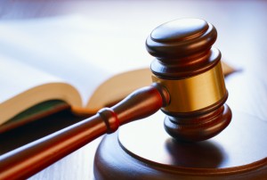 brown gavel and open book on a wooden table of the law in the courtroom